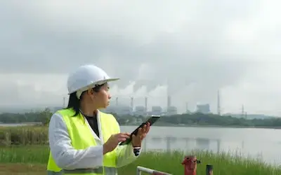 Female worker in safety gear using tablet for environmental monitoring