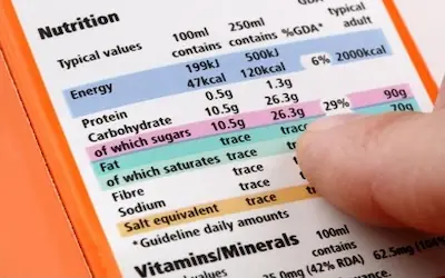 Person holding nutritional label on food product, providing nutritional info.
